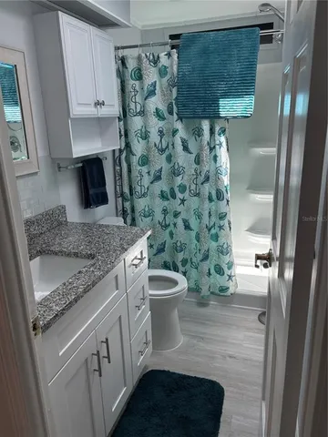 a bathroom with a granite countertop sink a toilet and shower
