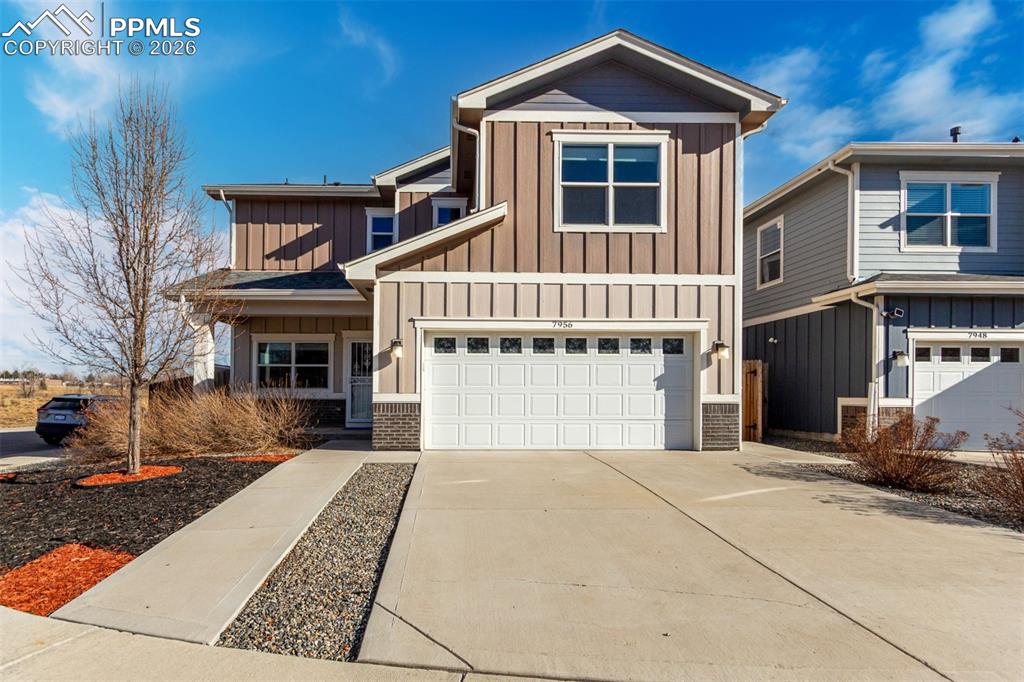 7956 Osage Street Denver, CO 80221 - Photo 2 of 48 Craftsman-style house with board and batten siding, concrete driveway, an attached garage, and covered porch
