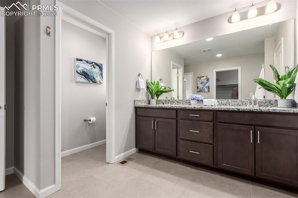 7956 Osage Street Denver, CO 80221 - Photo 22 of 48 Full bath with double vanity, a spacious closet, and light tile patterned flooring