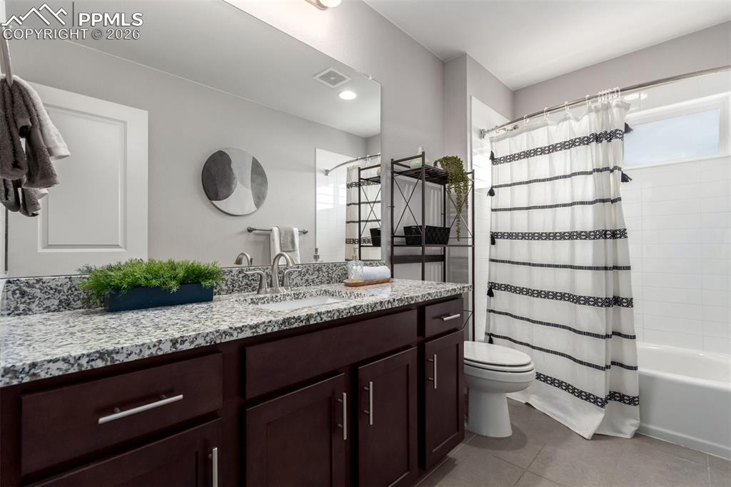 7956 Osage Street Denver, CO 80221 - Photo 26 of 48 Bathroom featuring vanity, shower / bath combo with shower curtain, and light tile patterned flooring