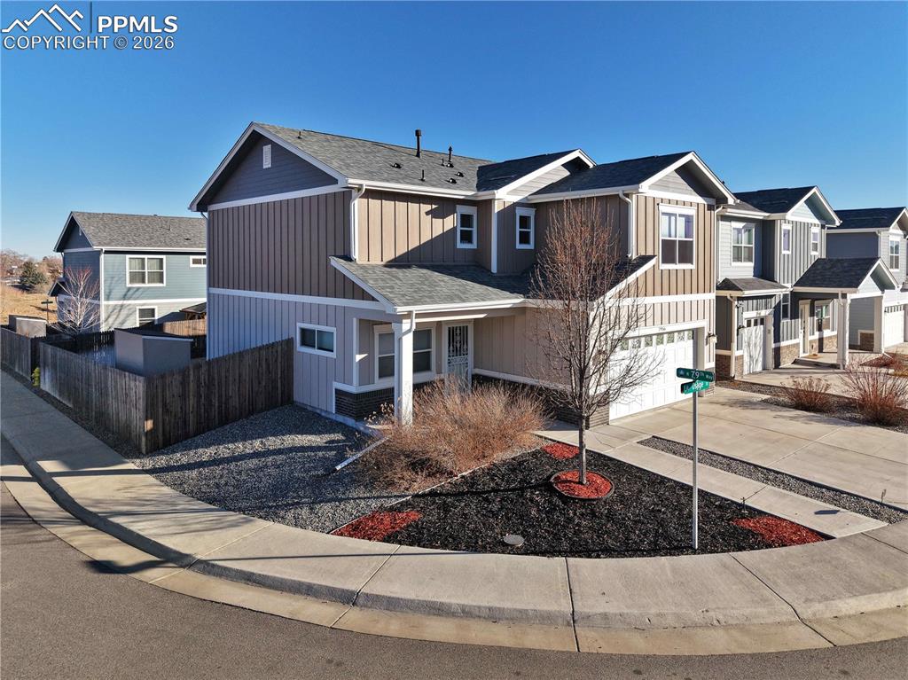 7956 Osage Street Denver, CO 80221 - Photo 37 of 48 Traditional-style home with concrete driveway, board and batten siding, a residential view, an attached garage, and covered porch