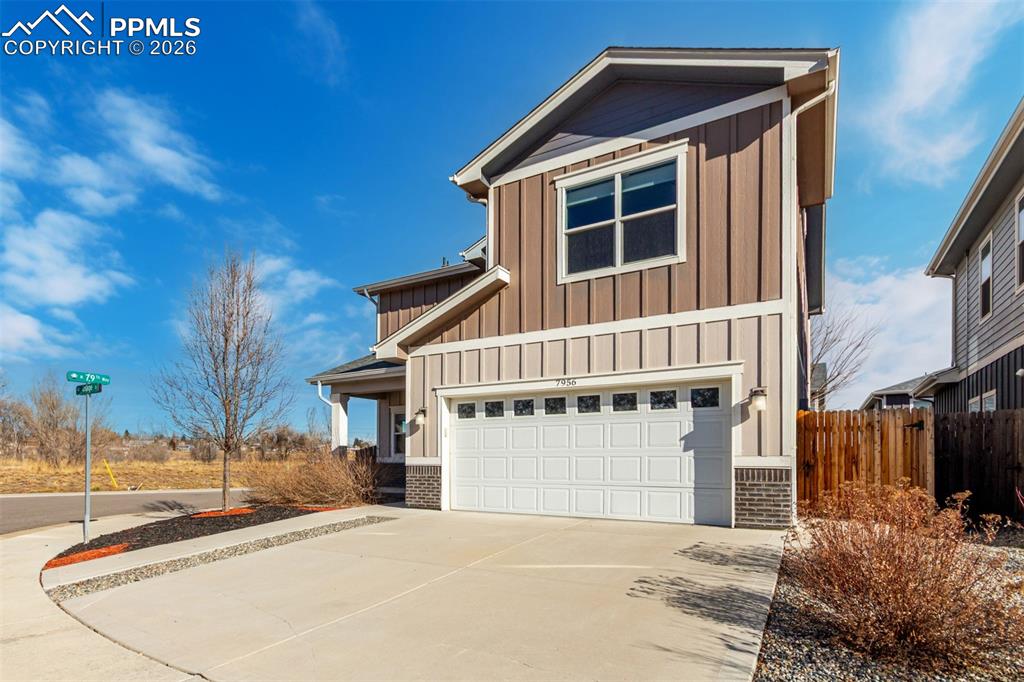 7956 Osage Street Denver, CO 80221 - Photo 44 of 48 View of front facade featuring driveway, brick siding, board and batten siding, and an attached garage