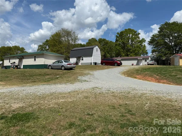 a view of a house with a yard and large trees