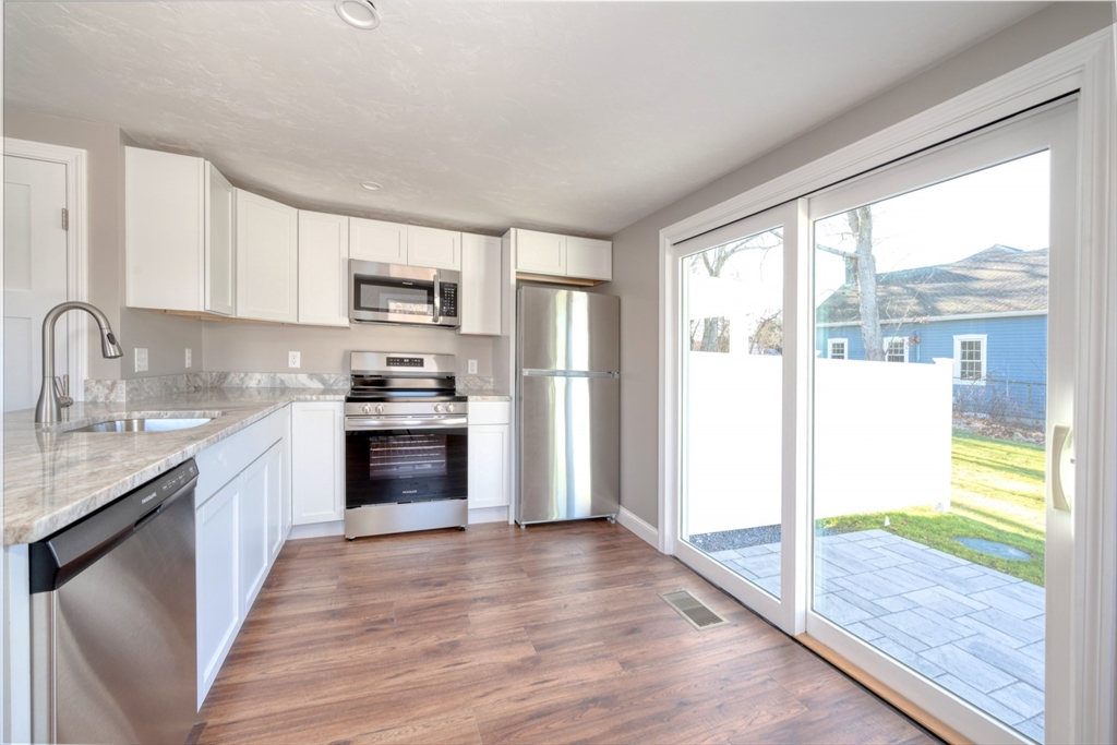 665 State Road, Unit 1 Plymouth, MA 02360 - Photo 6 of 13 a kitchen with granite countertop a stove a sink and a refrigerator