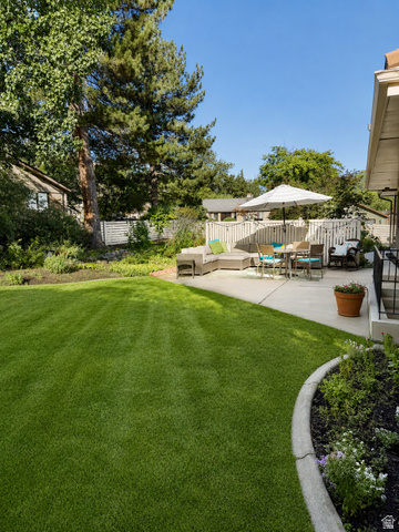 2924 Robidoux Road Sandy, UT 84093 - Photo 53 of 68 Expansive lawn area with mature trees, concrete patio, and garden beds with curb edging