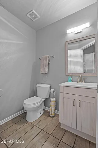 a bathroom with a granite countertop toilet a sink and a mirror