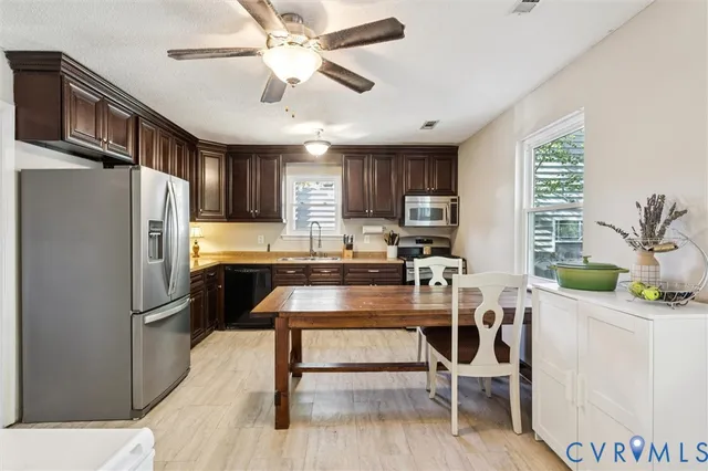 a kitchen with granite countertop a refrigerator a stove a sink dishwasher a oven a dining table and chairs with wooden floor