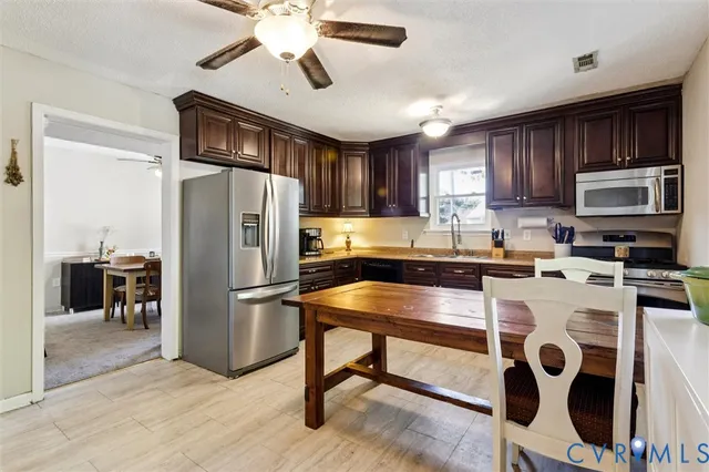 a kitchen with stainless steel appliances granite countertop a refrigerator a stove a sink a microwave and island with wooden floor