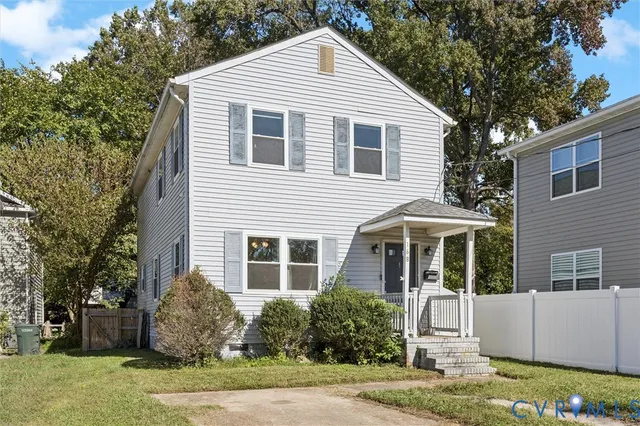 a view of a white house next to a yard with big trees