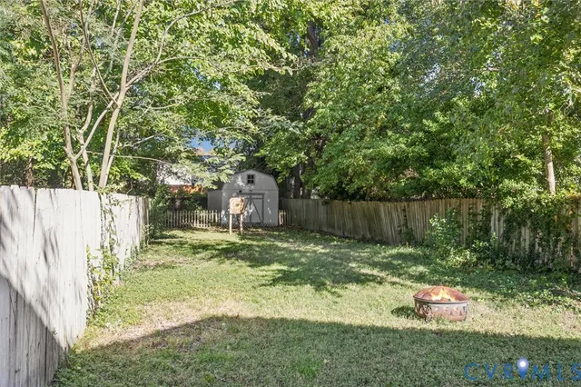a backyard of a house with large trees and wooden fence