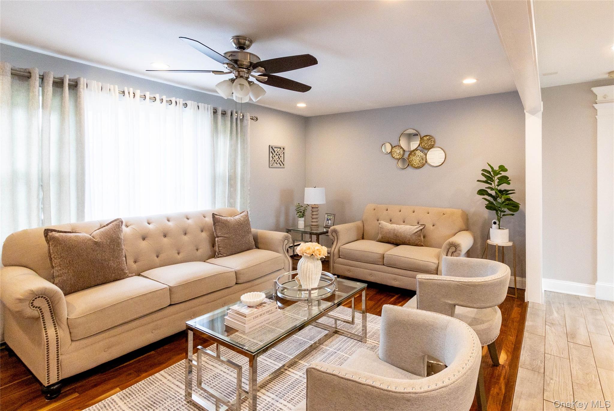 151 Cheltenham Road West Babylon, NY 11704 - Photo 13 of 42 Open-concept living space featuring wood-finish flooring, a contemporary ceiling fan, recessed lighting, and a large window with sheer curtains