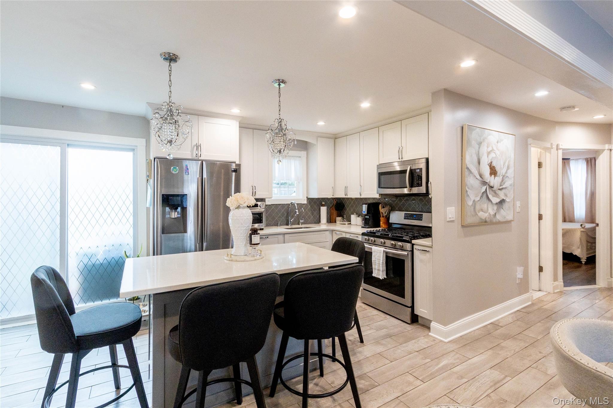 151 Cheltenham Road West Babylon, NY 11704 - Photo 18 of 42 Modern kitchen featuring stainless steel appliances, white cabinetry, a light-toned countertop island, wood-finish flooring, and recessed lighting