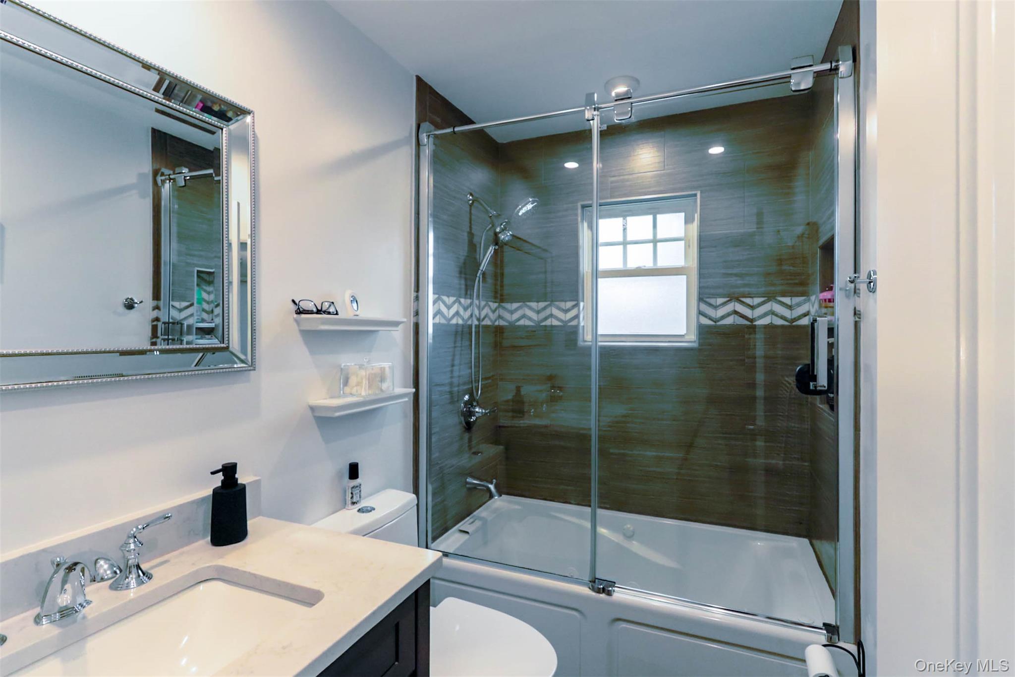 151 Cheltenham Road West Babylon, NY 11704 - Photo 25 of 42 Bathroom featuring a tub/shower combination with glass enclosure, brown horizontal tile, and chevron accent tile