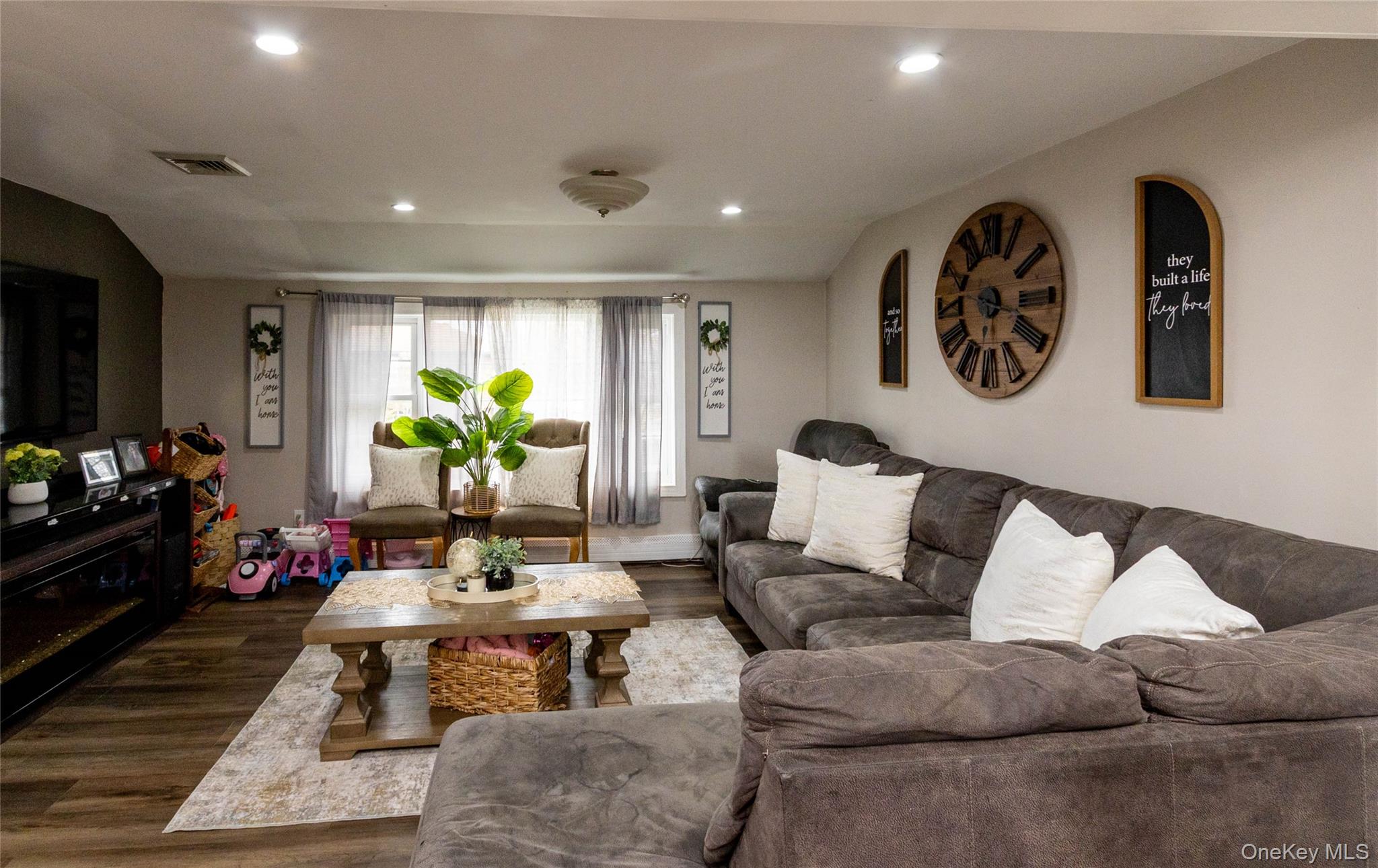 151 Cheltenham Road West Babylon, NY 11704 - Photo 27 of 42 Open concept living area featuring wood-finish flooring, recessed lighting, a large window with sheer and blackout curtains, and neutral wall tones