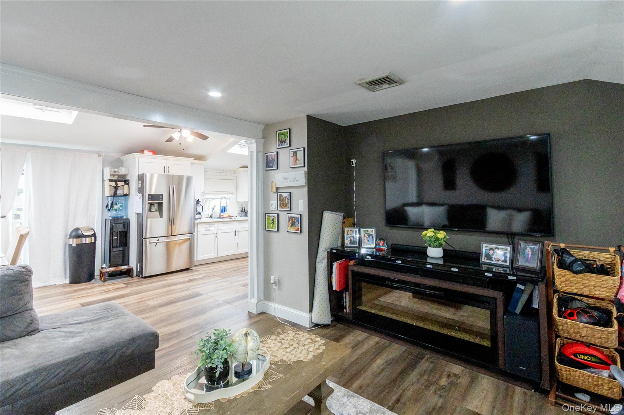 151 Cheltenham Road West Babylon, NY 11704 - Photo 30 of 42 Open-concept living area featuring wood-finish flooring, a contemporary dark accent wall, recessed lighting, and a built-in media console with an electric fireplace