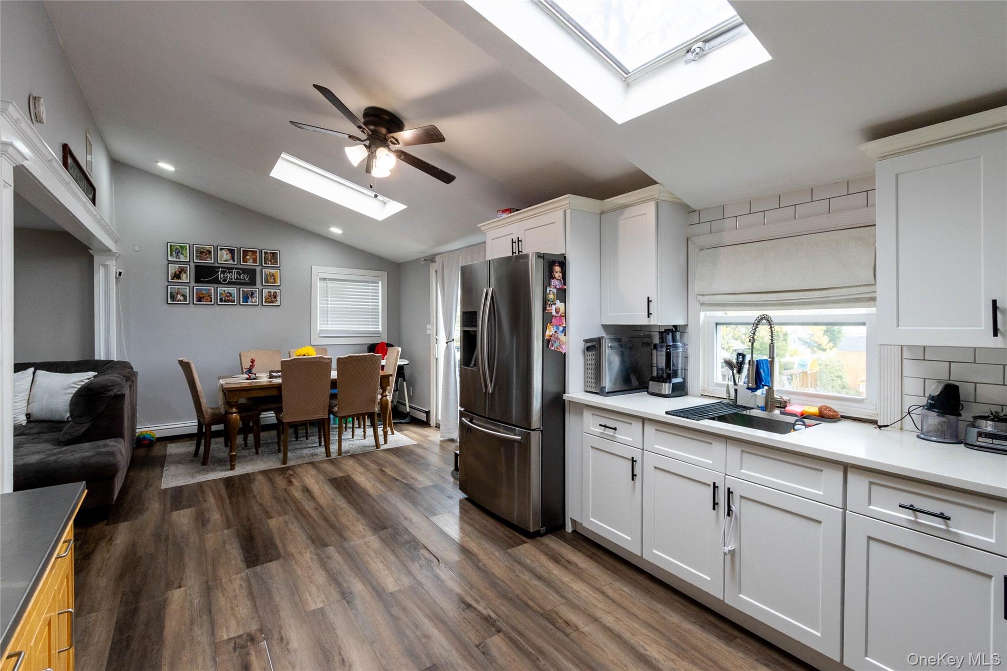 151 Cheltenham Road West Babylon, NY 11704 - Photo 31 of 42 Modern kitchen featuring white shaker cabinetry, stainless steel refrigerator, white subway tile backsplash, and quartz countertops with an undermount sink