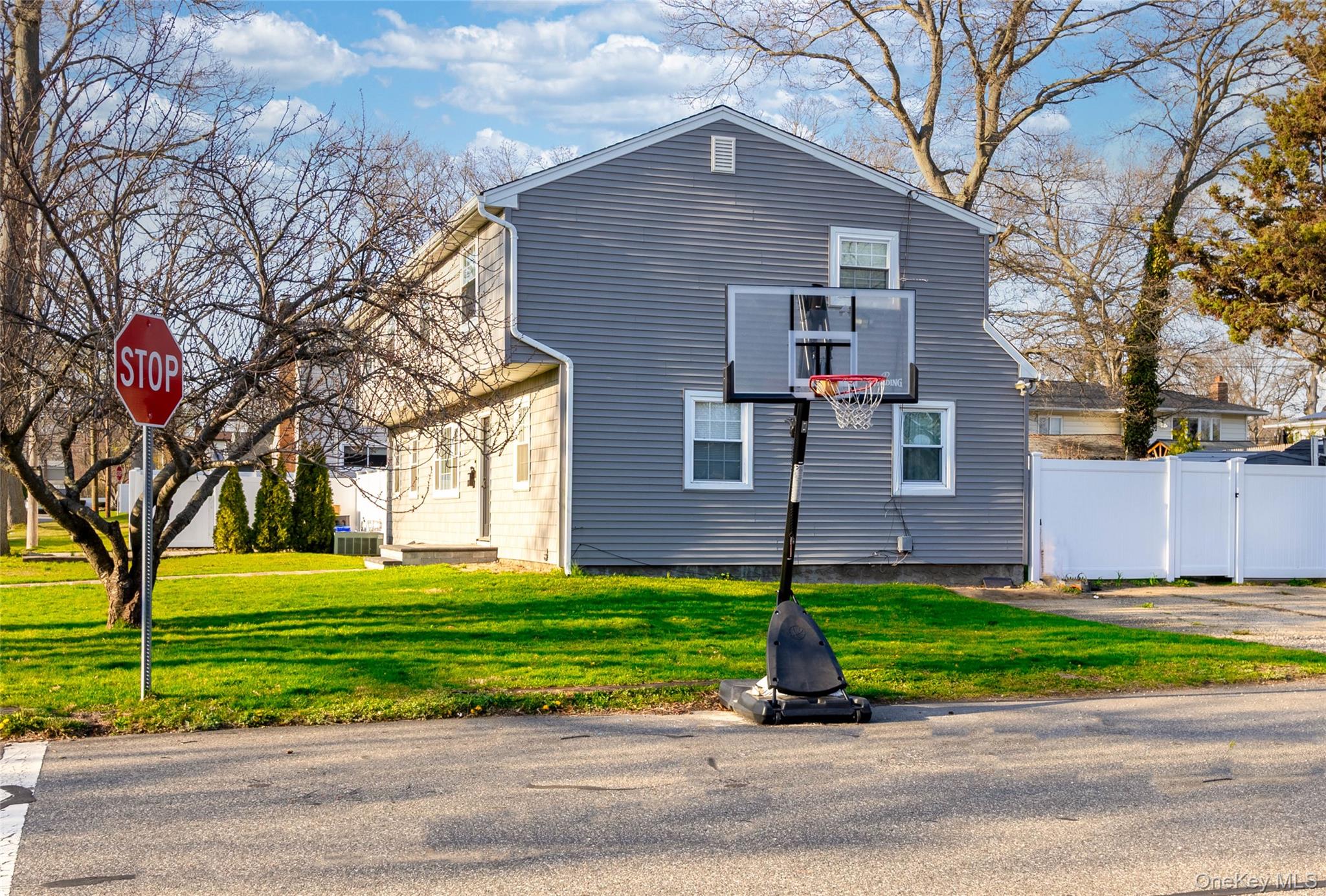 151 Cheltenham Road West Babylon, NY 11704 - Photo 4 of 12 The property features gray siding, white trim windows, and a well-maintained lawn