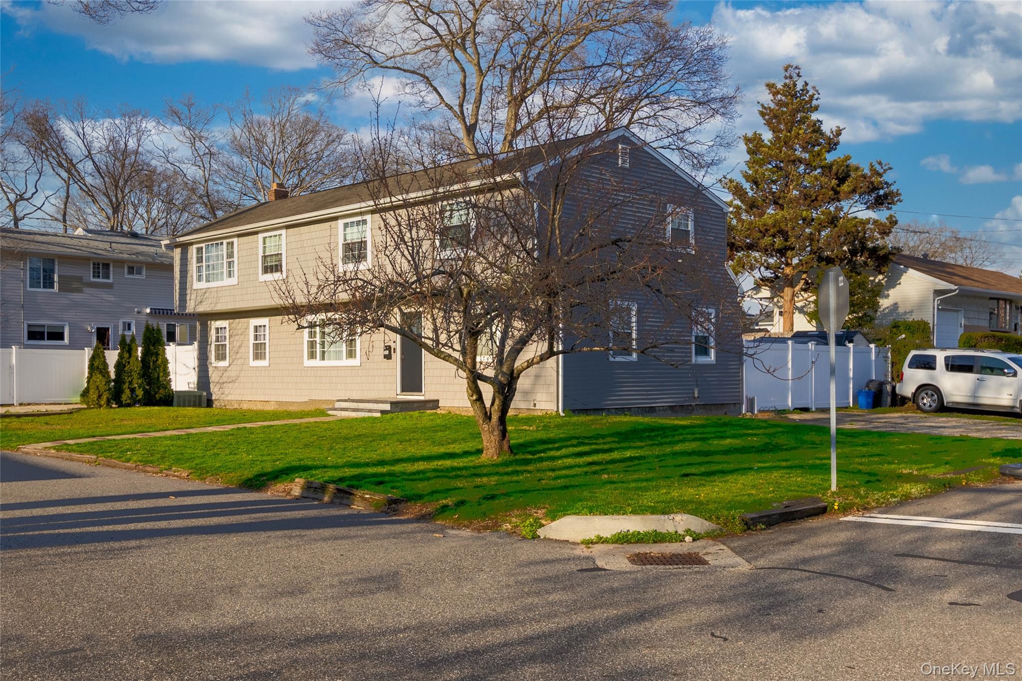 151 Cheltenham Road West Babylon, NY 11704 - Photo 5 of 12 The property features a two-story exterior with siding, a front entry, and a well-maintained lawn
