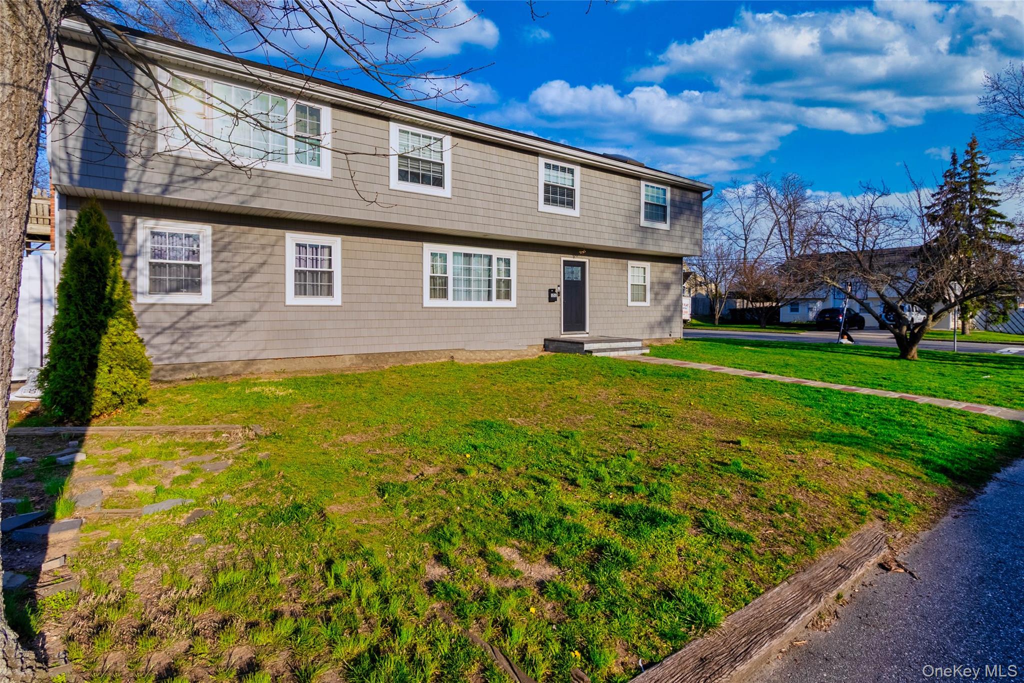 151 Cheltenham Road West Babylon, NY 11704 - Photo 6 of 12 The property features a two-story exterior with horizontal siding, white-trimmed windows, and a dark front door