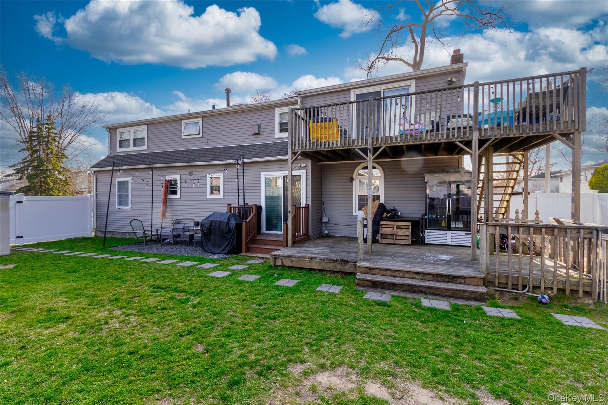 151 Cheltenham Road West Babylon, NY 11704 - Photo 7 of 12 The property features a spacious rear yard with a lawn, a ground-level deck, and an upper-level deck