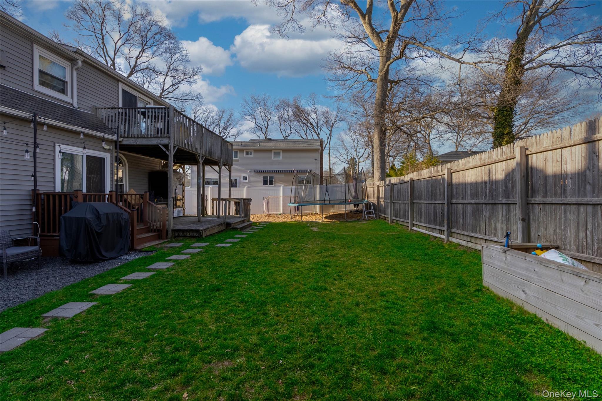 151 Cheltenham Road West Babylon, NY 11704 - Photo 9 of 12 The property features a spacious backyard with a well-maintained lawn and a wooden privacy fence