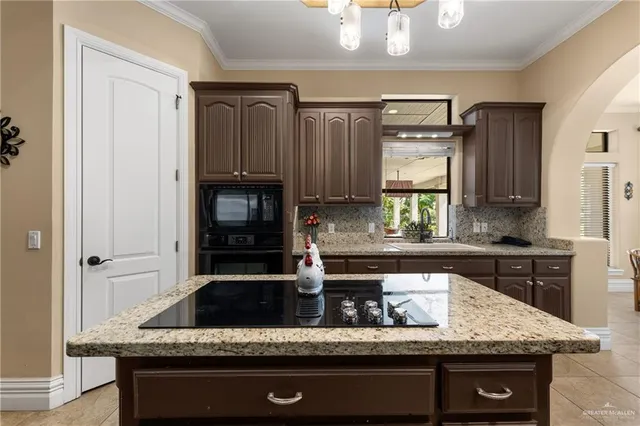 a kitchen with granite countertop a sink a stove and cabinets