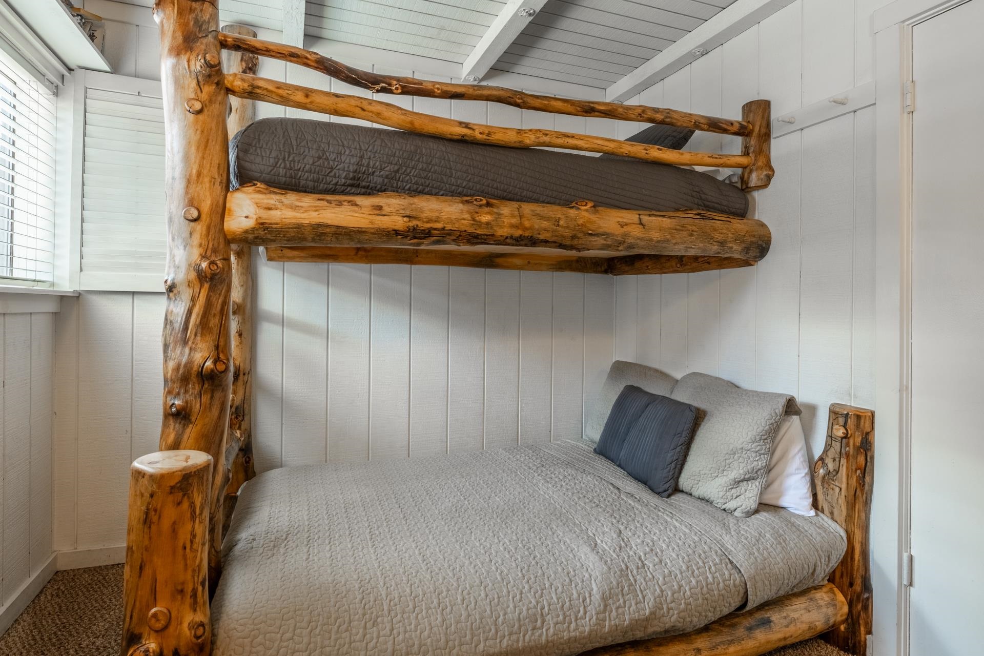 165 Old Mammoth Road, Unit 3 Mammoth Lakes, CA 93546 - Photo 25 of 48 Custom log bunk beds featuring natural wood construction, white vertical plank walls, a window with horizontal blinds, and a textured ceiling