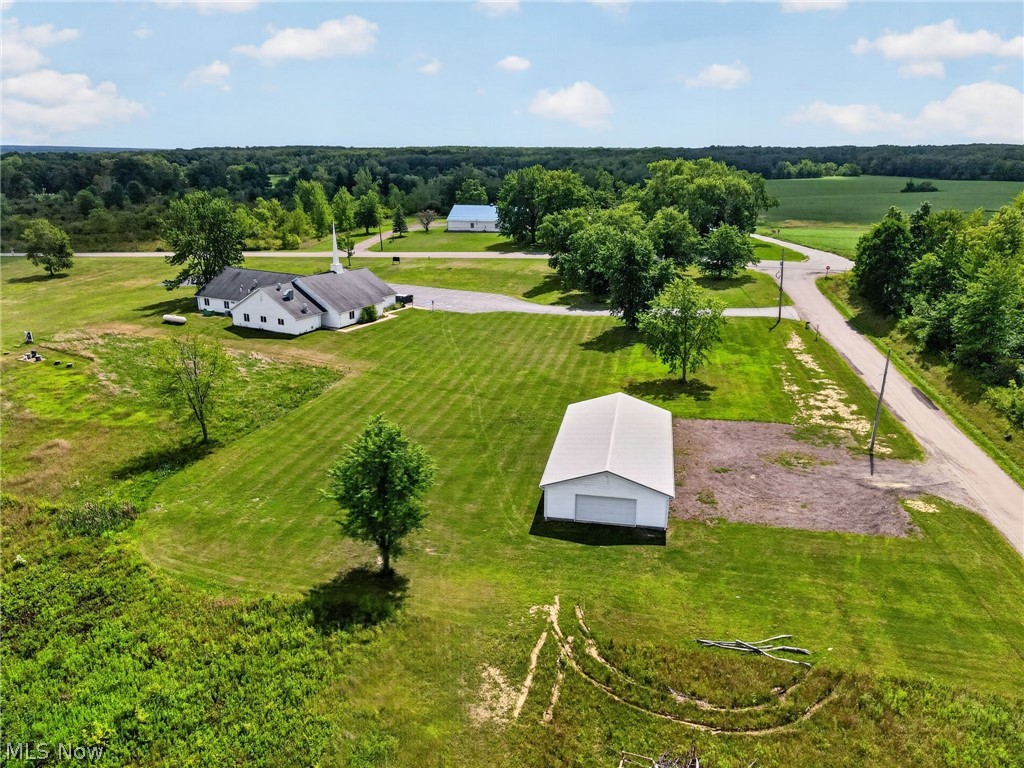 Expansive green space with an additional detached building and a gravel parking area