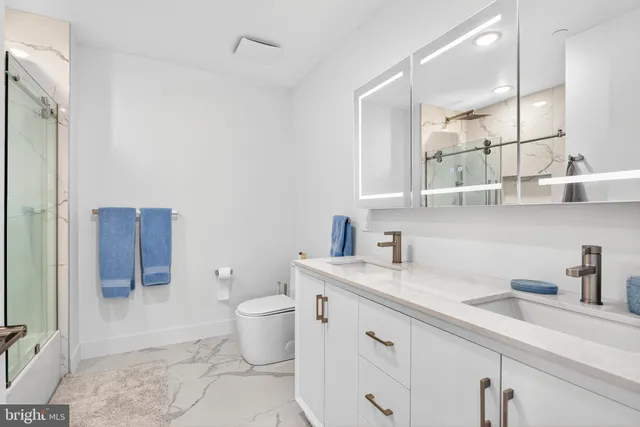 a bathroom with a granite countertop sink a toilet and a mirror
