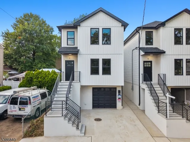 a view of a white house with large windows and couches chairs