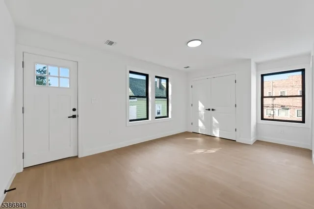 a view of an empty room with a window and wooden floor