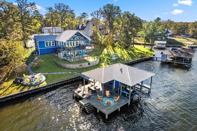 an aerial view of a house with swimming pool a patio and lake view