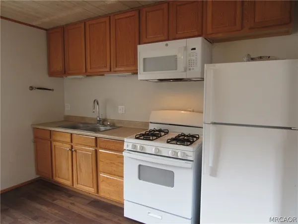 a kitchen with stainless steel appliances granite countertop a refrigerator stove a sink and dishwasher with wooden floor