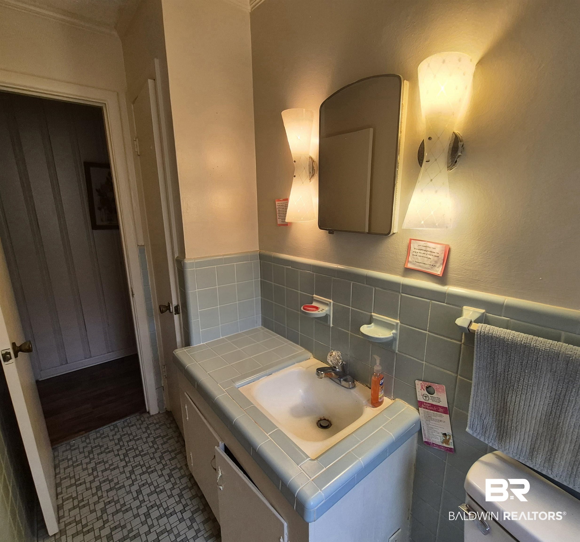 108 Azalea Street Evergreen, AL 36401 - Photo 11 of 19 Bathroom featuring a single vanity with an integrated sink, light blue tiled countertop, light blue wall tiling, and dual wall-mounted sconces