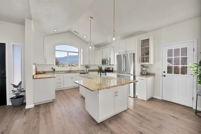 a large white kitchen with a lot of counter space and a wooden floor