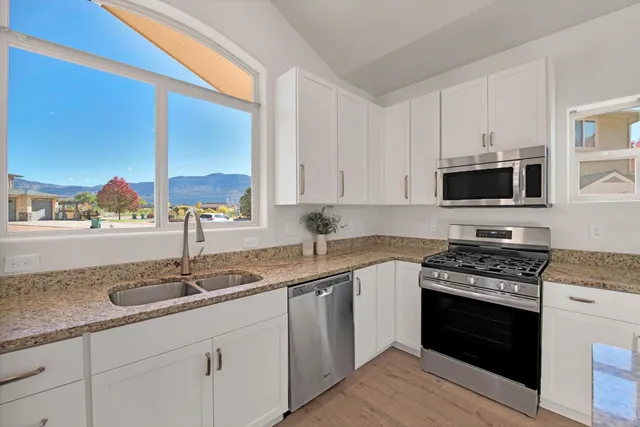 a kitchen with stainless steel appliances granite countertop a sink stove and microwave