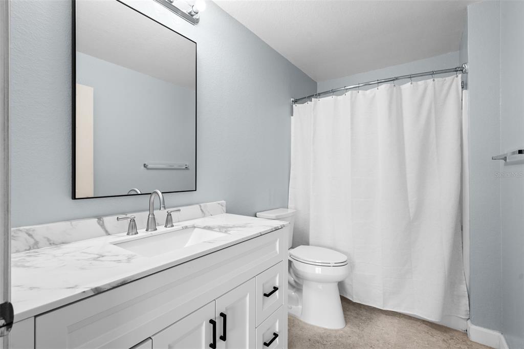 5459 Vineland Road, Unit 4302 Orlando, FL 32811 - Photo 14 of 25 a bathroom with a granite countertop sink a toilet and a mirror