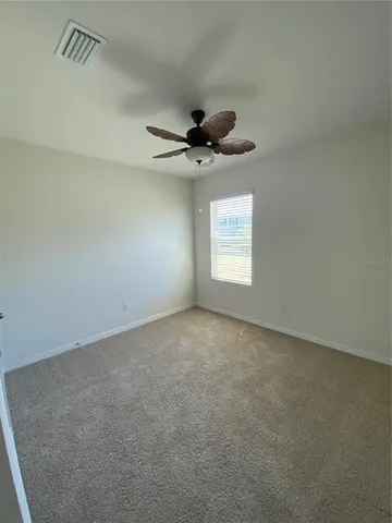 an empty room with windows and ceiling fan