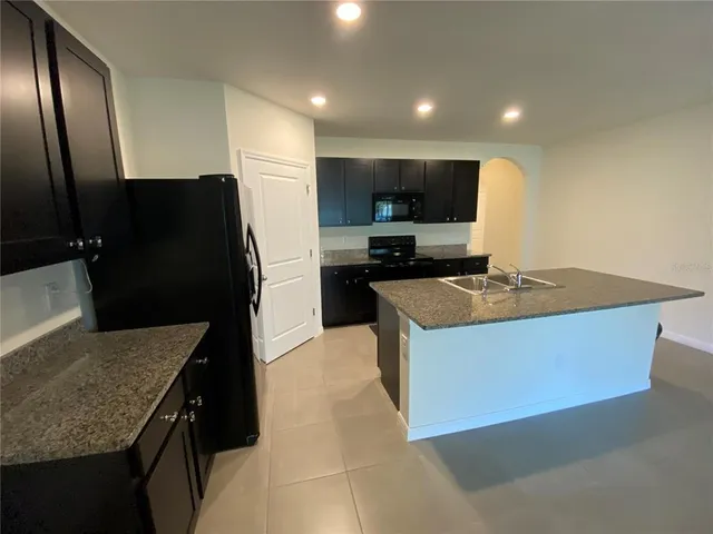 a kitchen with stainless steel appliances granite countertop a sink a stove a refrigerator a microwave a sink and a refrigerator