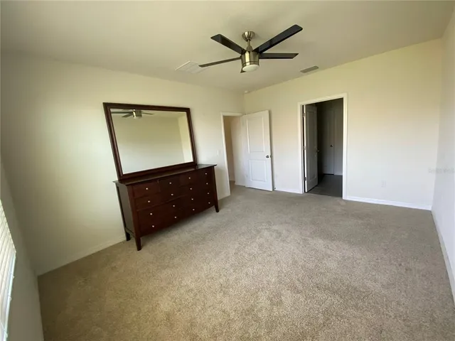 an empty room with mirror and a ceiling fan