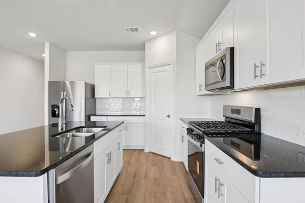a kitchen with kitchen island granite countertop a sink stainless steel appliances and cabinets