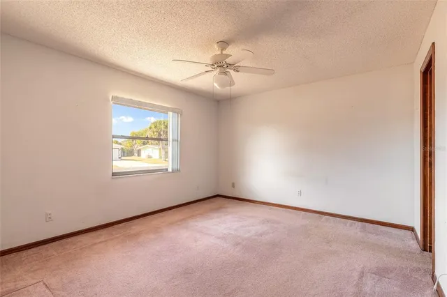 an empty room with windows and fan