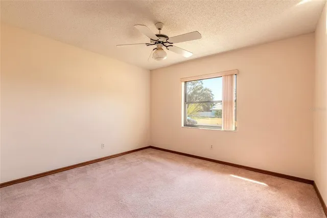 an empty room with a window and a fan