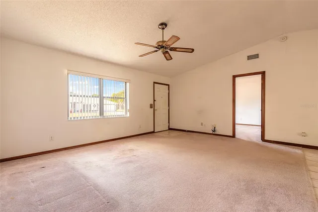 an empty room with windows and ceiling fan