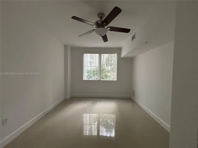 an empty room with windows and ceiling fan