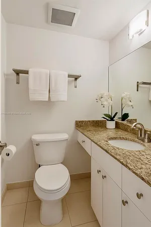 a bathroom with a granite countertop toilet sink and mirror