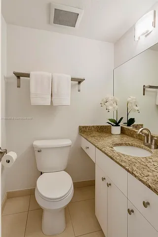 a bathroom with a granite countertop toilet sink and mirror