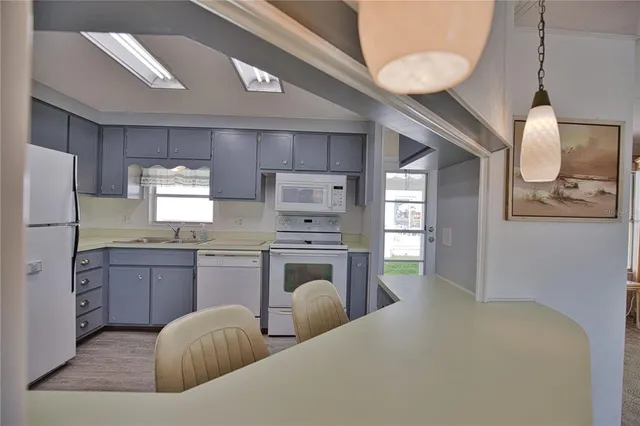 a kitchen with stainless steel appliances a white stove top oven cabinets and a wooden floor