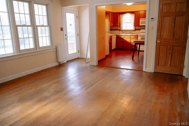 an empty room with wooden floor and a kitchen