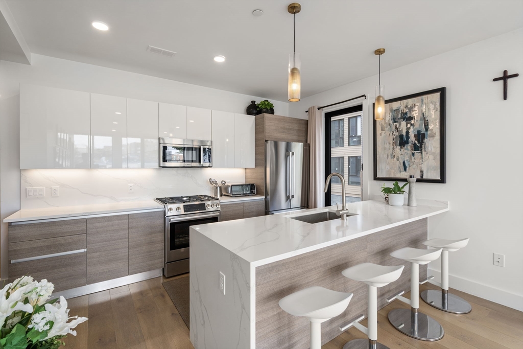30 Penniman Road, Unit 201 Boston, MA 02134 - Photo 6 of 23 a kitchen with stainless steel appliances granite countertop a stove and white cabinets